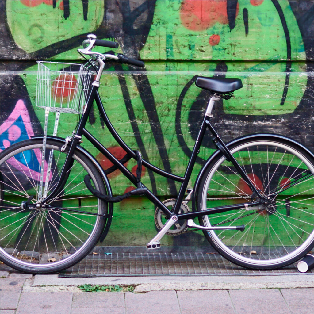 Svart cykel framför graffitivägg. Foto av Silvia Lupuianu.